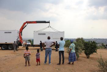 A group stands outside a Solar Learning Lab which is being placed