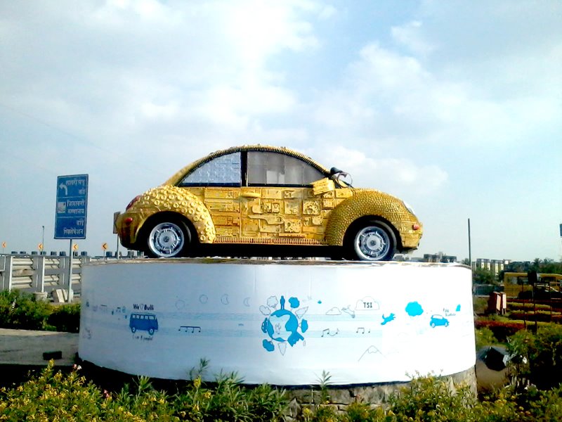 A bright yellow Volkswagen beetle made of scrap material